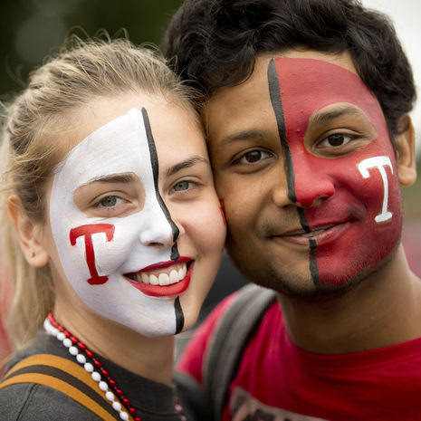 Students with Temple themed face paint smiling during Homecoming.
