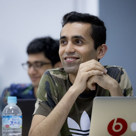 A smiling student sitting in front of his laptop in class
