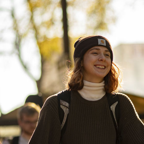 A smiling student wearing a winter beanie walking on Main Campus