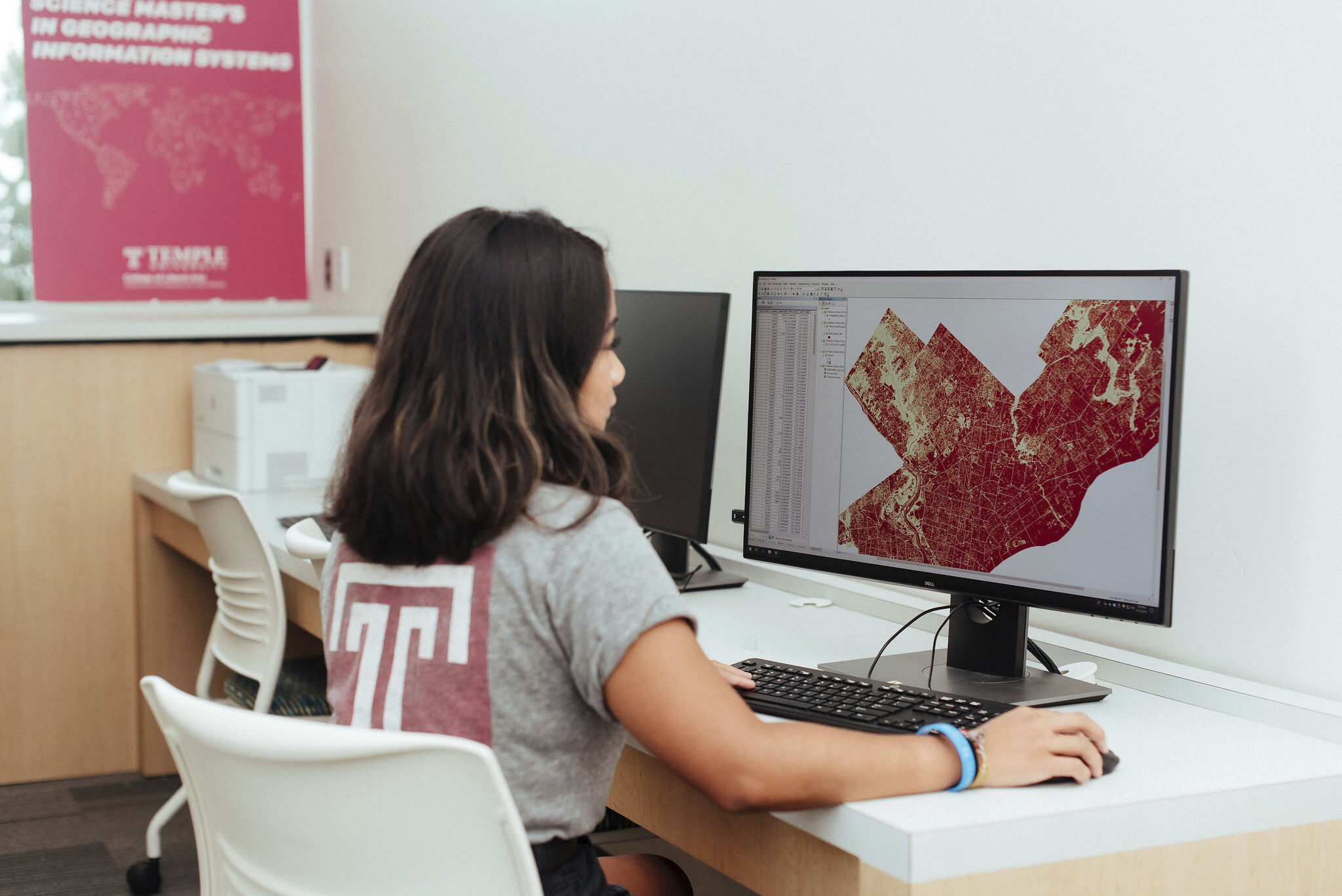 A student sitting at a computer and working on a GIS map.