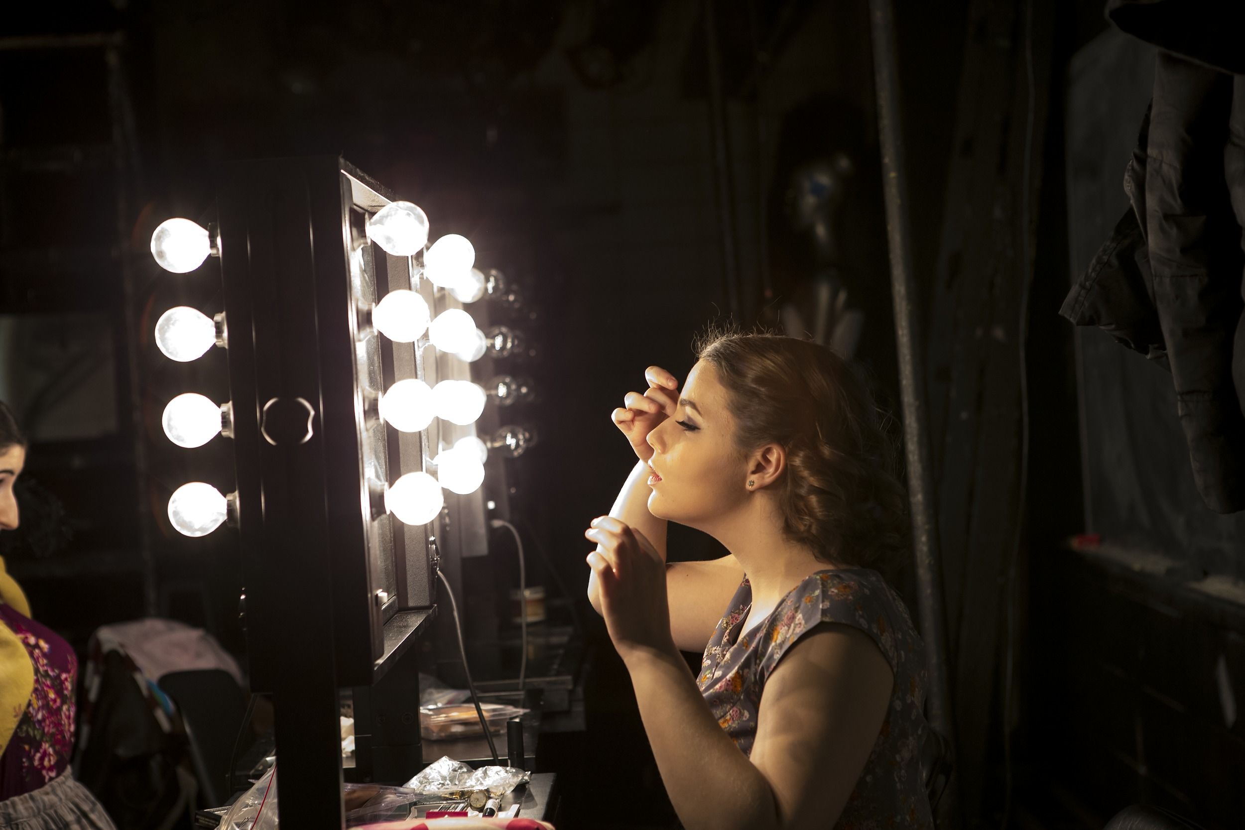 A Temple student applies makeup backstage.