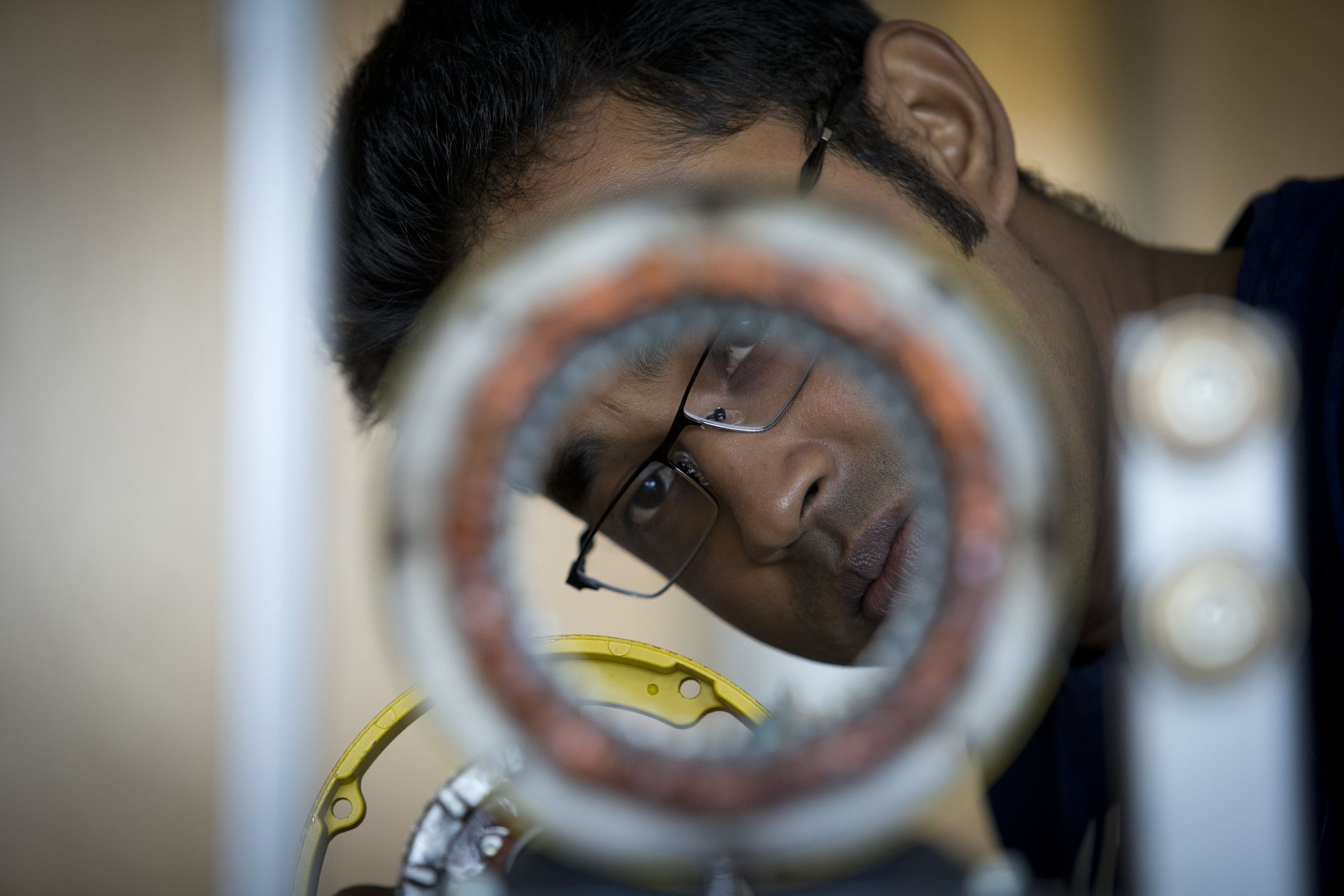 A student face can be seen through a circular engineering device.