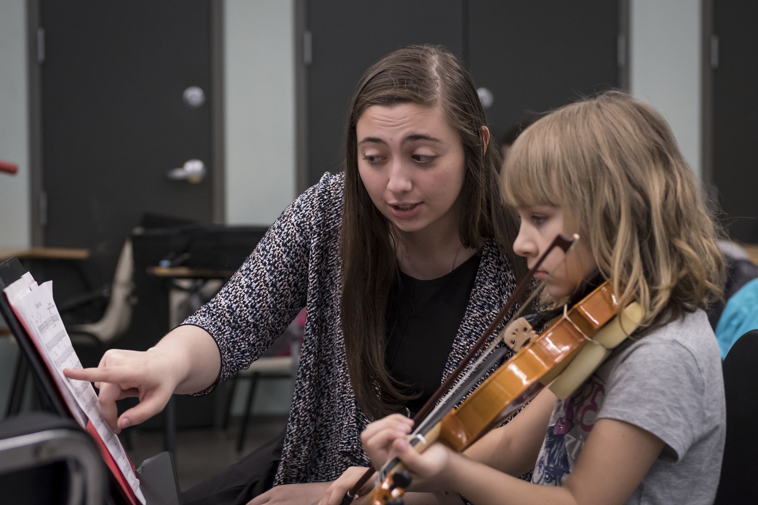 A Temple student teacher helps a pupil to read sheet music.