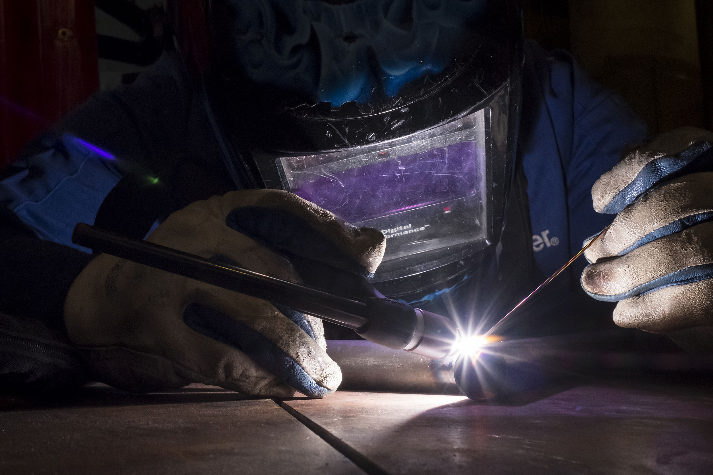 An engineering student wears gloves and a mask while welding.