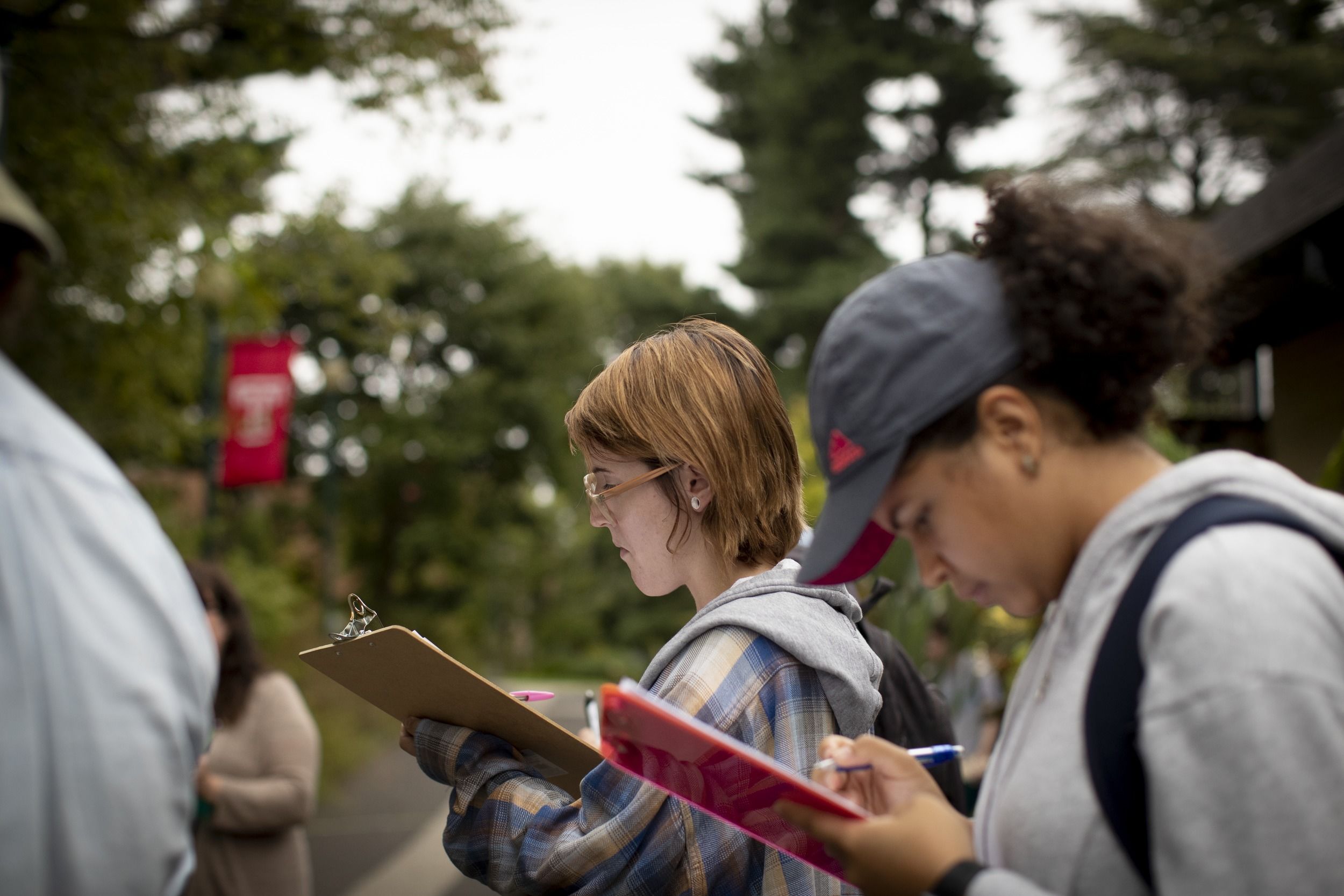 Students take notes on clipboards while standing outside at Ambler Campus.