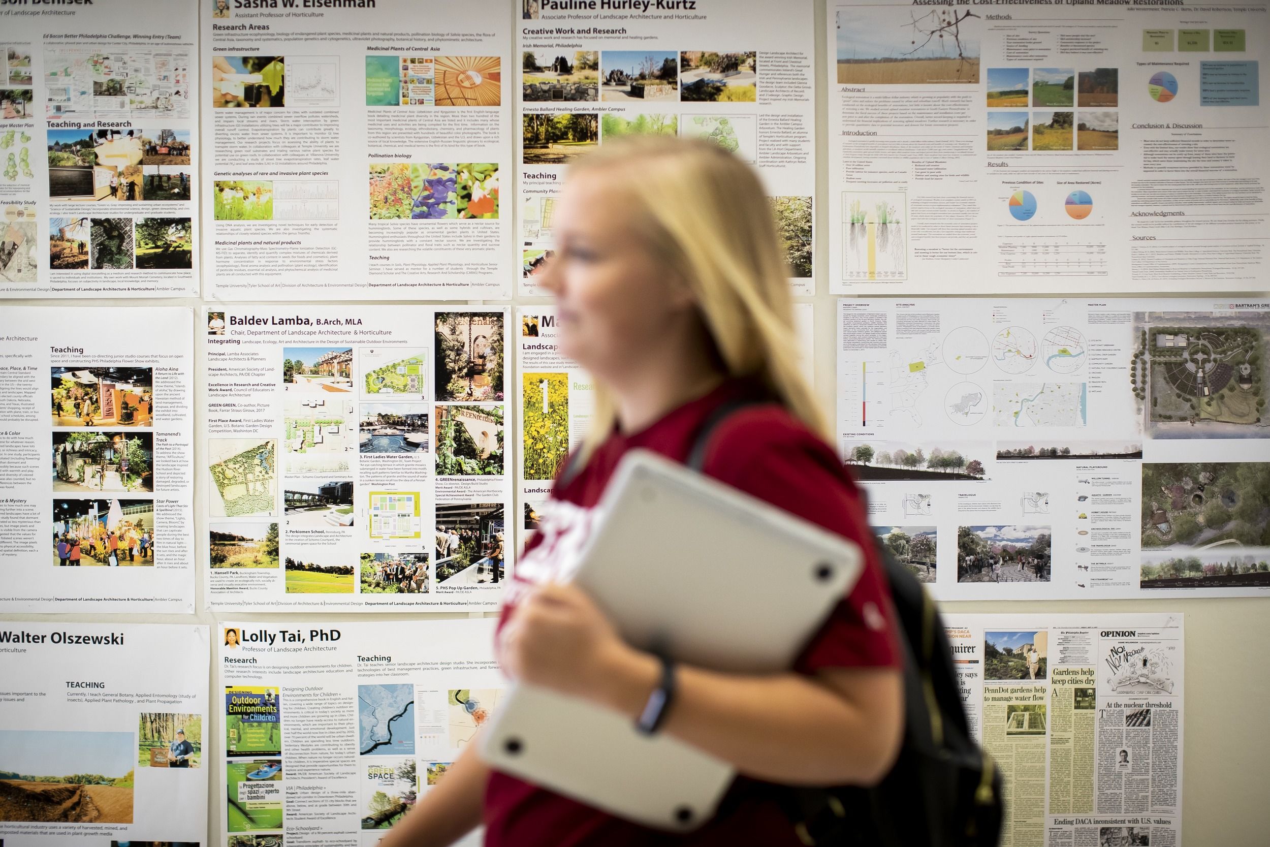 A student rushes past a bulletin board filled with academic posters.