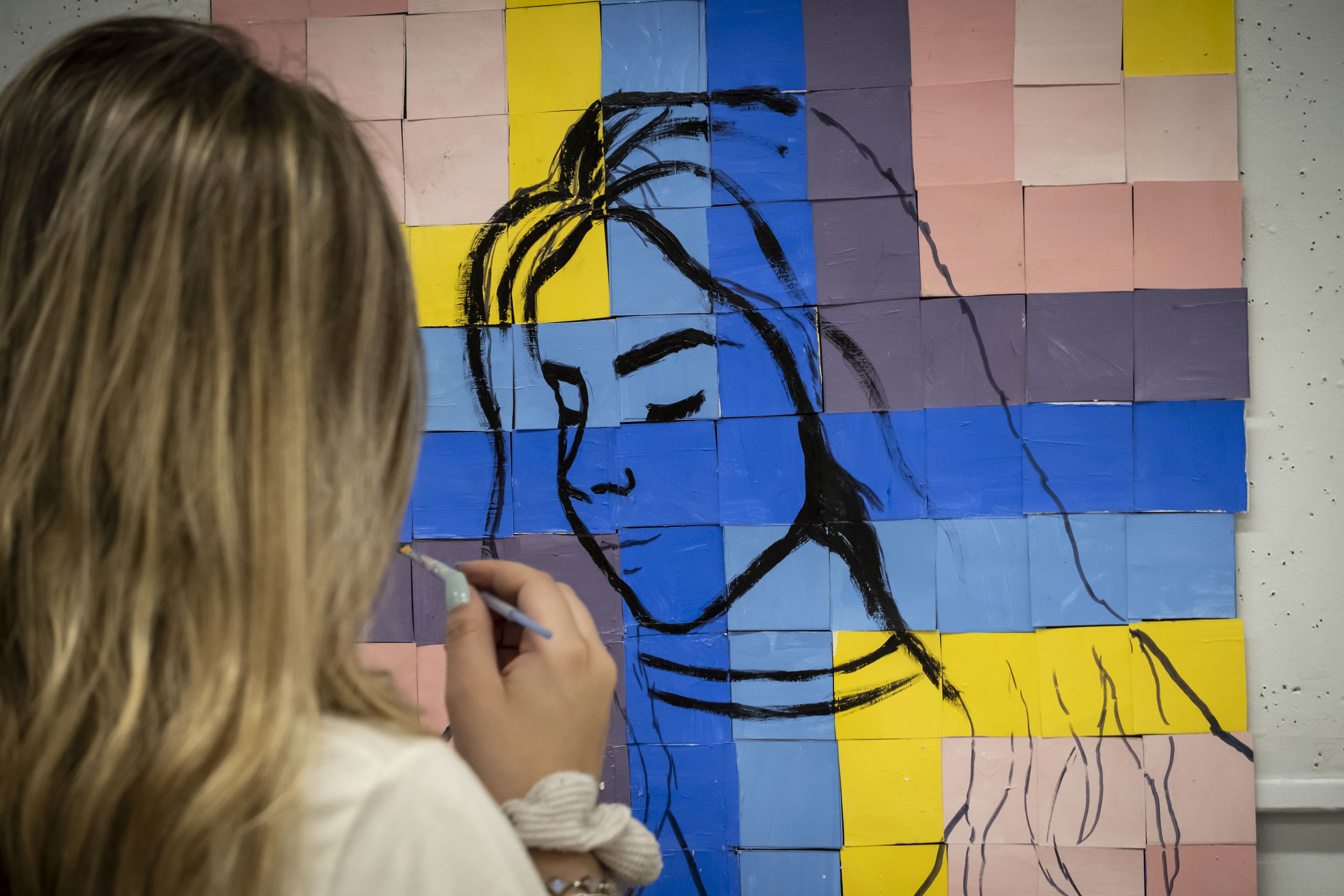 Female student painting a self portrait.