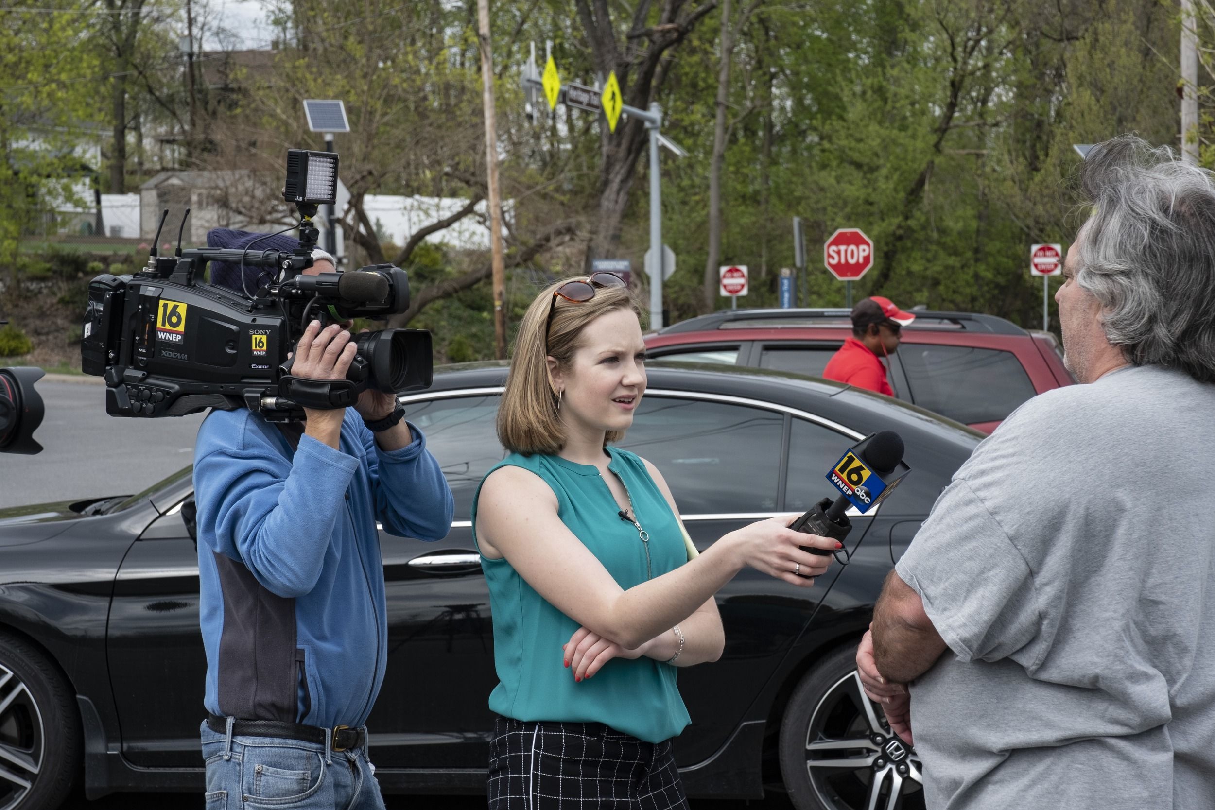 A student reporter holds a microphone while interviewing a person on the street.
