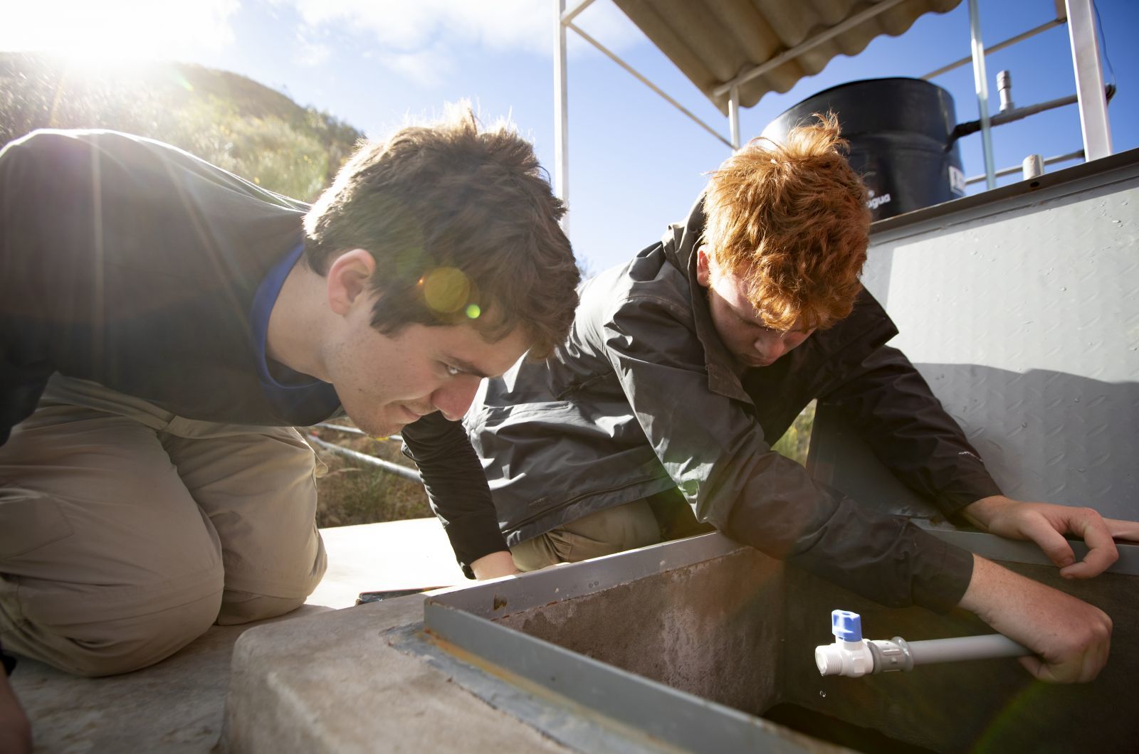 Two students building a water tank while away on a study abroad project.