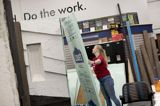 A student holding a large piece of drywall.