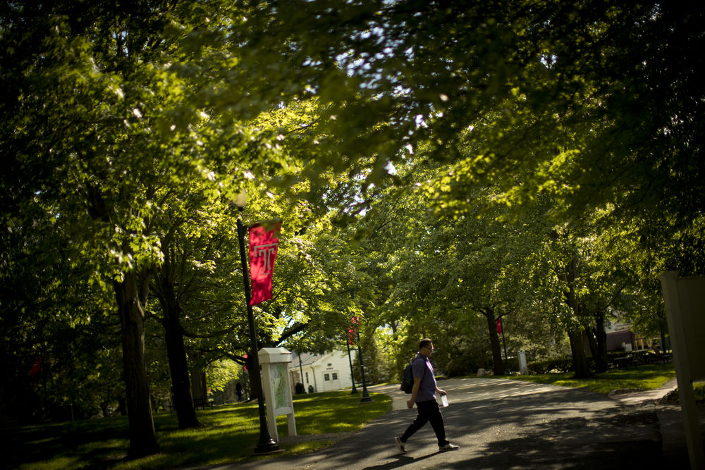 A student walking across Ambler Campus on a fall day